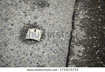 A shot of a relic from the past, a floppy disk that has been destroyed and discarded like garbage on the cement pavement to be washed away from history