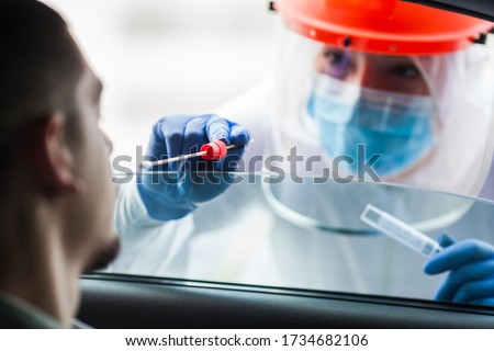 COVID-19 drive-thru patient specimen collection,female medical worker performing nasal swab on young man through vehicle window,Coronavirus point of care rt-PCR diagnostic at testing site location  Royalty-Free Stock Photo #1734682106