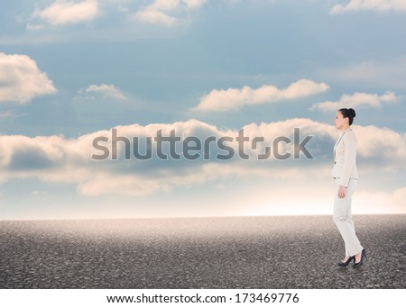 Unsmiling asian businesswoman walking against desert landscape with blue sky