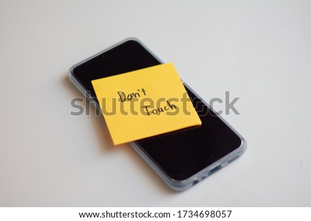 Text "don'touch" on paper note on smart phone. Digital detox, dependency on tech, no gadget and devices concept.