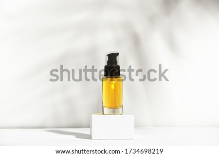 Unbranded bottle with dispenser on pedestal. Transparent glass container with oil for body and hair. Display sample on shadow background. Mockup style design. Cosmetology and beauty concept Royalty-Free Stock Photo #1734698219