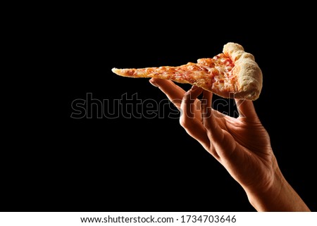 Hand holding slice of cheese pizza cut in slices