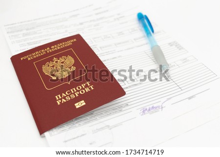 The Russian passport contains documents for filling in data and signatures on a white background. There is a pen on the sheet.