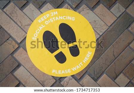 Social distancing pavement sticker advising the safe distance to maintain to avoid desease contraction.