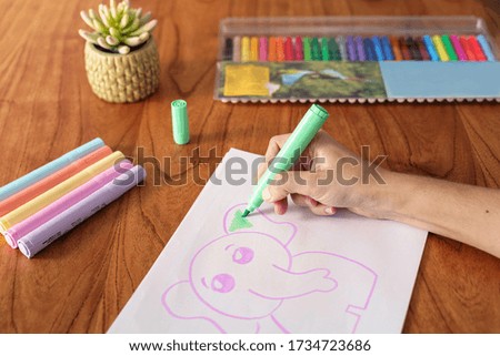 Hands of a woman drawing with colored markers at home