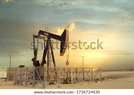 An oil pump jack with a beautiful sunset in the background