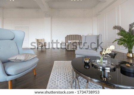 Modern luxury stylish apartment interior in pastel colors. a very bright room with huge windows filled with daylight. white walls, wooden parquet floors and a dark marble fireplace