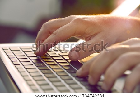 Closeup of man’s hands typing on laptop keyboard.