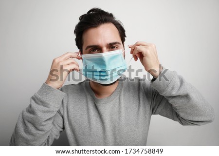 Headshot of young man using medical virus mask protection of coronavirus. Worldwide pandemic situation. Royalty-Free Stock Photo #1734758849