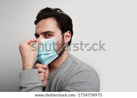 Headshot of young man using medical virus mask protection of coronavirus. Worldwide pandemic situation. Royalty-Free Stock Photo #1734758975