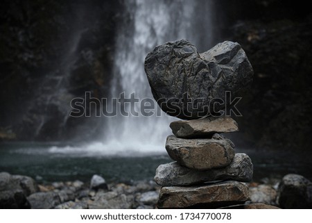 a stack of rocks by a waterfall 