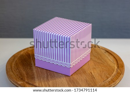 pink gift box with stripes on a wooden stand