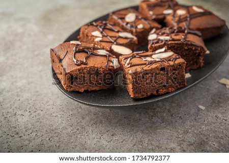 Homemade brownies with almond petals on a dark plate on a wooden background. Close up. Selective focus