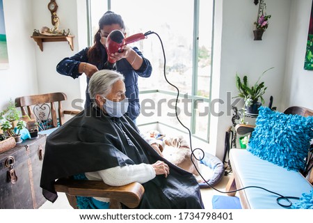 Senior woman getting a haircut at home during Covid-19 pandemic wearing face mask Royalty-Free Stock Photo #1734798401