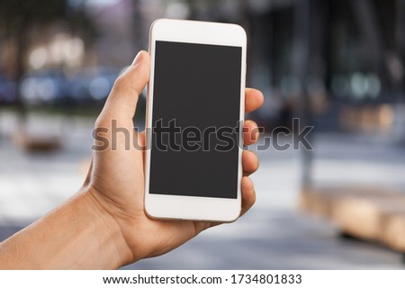 A woman holding a mobile phone with a blank screen.