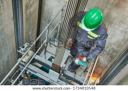 lift machinist repairing elevator in lift shaft Royalty-Free Stock Photo #1734810548