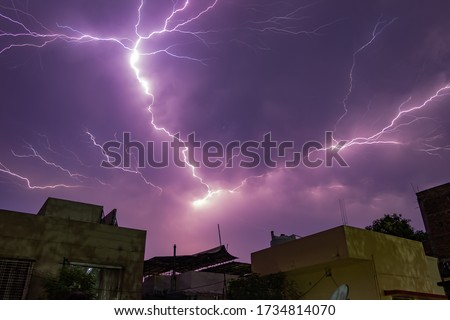 Lightning bolts of approaching thunderstorm over residential buildings.