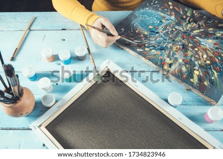 woman hand brush paint on canvas on table