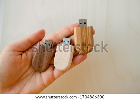 Female hand holds a set of three stylish wooden flash drives on a light background. set for the photographer, presentable of photos, luxury

