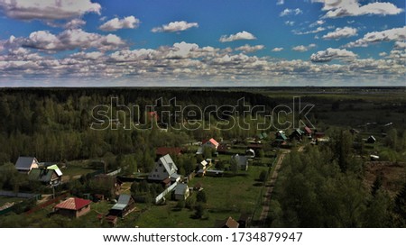 Сlouds are floating in the blue sky over the village and the forest.