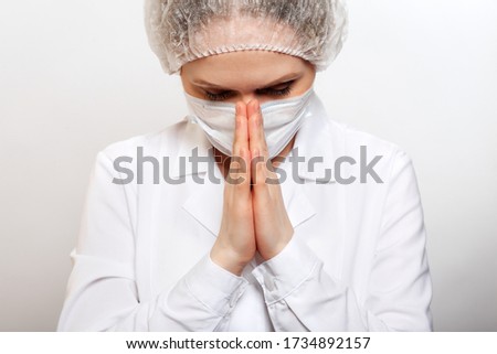 Beautiful white girl doctor or nurse, prays to God, asking that the coronovirus stop. Global pandemic coronavirus or Covid-19.