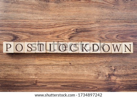 Post-lockdown text on building blocks on wooden desk background. Adapting to new life or business post-lockdown after COVID pandemic. Business with social distancing personal hygiene Royalty-Free Stock Photo #1734897242