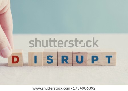 Hand holding wooden blocks with word DISRUPT, disruptive innovation way of business concept 