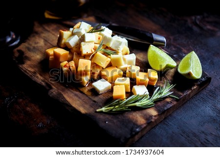 
Board with cheese, lemon oil on black background.