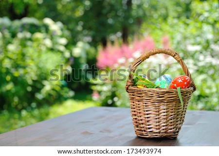   basket with painted eggs standing on garden table Royalty-Free Stock Photo #173493974