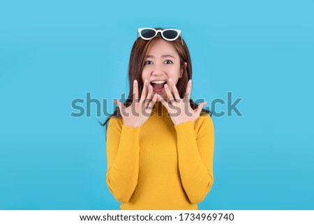 Beautiful Asian woman is shocked with open mouth. Isolated on a blue background.