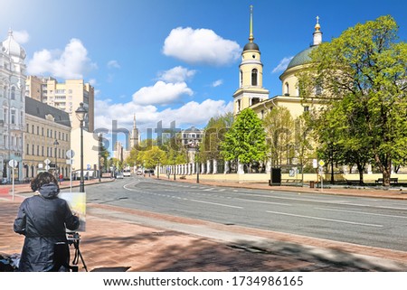 spring moscow city russia historic street architecture landmark with painter painting picture of old church on foreground against blue sky background. Street view of russian town historic downtown