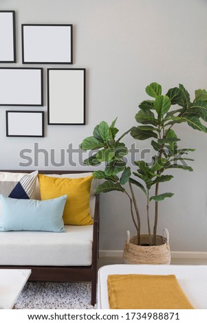 Fashionable living room interior with yellow and blue accents. Green plant pot and picture frame on wall in the room.