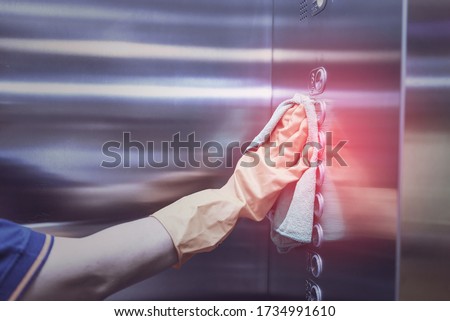 Woman hand in protective orange rubber gloves holding green microfiber cleaning cloth and wiping dust using a spray sterilizing solution make cleaning and disinfection for good hygiene Royalty-Free Stock Photo #1734991610