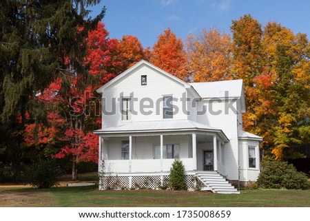 A beautiful view of an old white house surrounded by fall colour trees in Accident Maryland