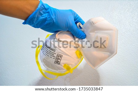 Hand with blue nitride gloves holding two type of N95 respirator face mask. 