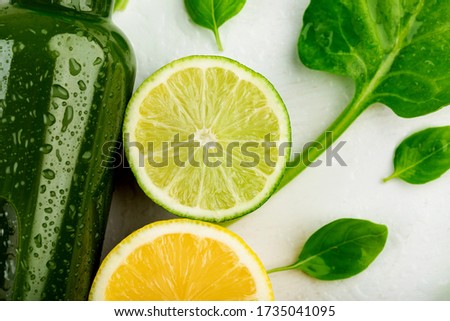 Slices of fresh citrus fruit and vegetables touching the side of a bottle filled with fresh fruit and vegetable juice. The concept of refreshing