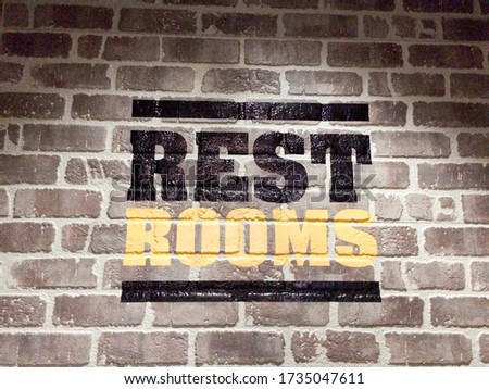 Restroom text for public bathroom sign on brick wall indoors