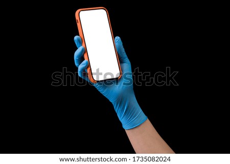 Doctor's hand in sterile medical gloves holding phone isolated on black background with clipping path. Concept of protection against pandemic and viruses.