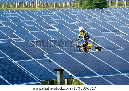 Group of engineer working on checking and maintenance with solar batteries near solar panels at sunny day in solar power plant station. Royalty-Free Stock Photo #1735096517