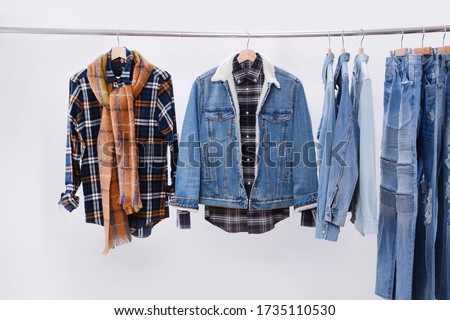 long sleeve colorful checkered shirt ,scarf, jeans , jeans jacket ,on wooden hanger on wooden rack over white background 



