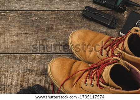 Close up photo of hiking boots and utility knife on wooden board