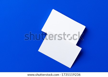 Blank white businesscards on classic blue background, copy space