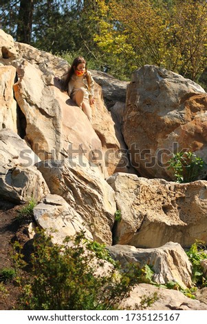 A young girl in a handmade mask goes down the stones in a beige cloak and trousers.
The photo was taken with selective focus.