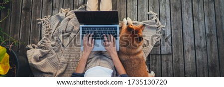 Header for website of young woman sitting on woodern terrace at home with dog using modern laptop device, Website banner