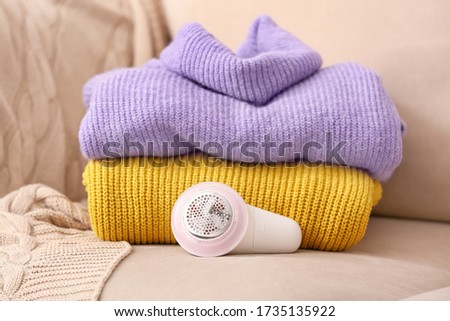 Modern fabric shaver and clothes on sofa Royalty-Free Stock Photo #1735135922