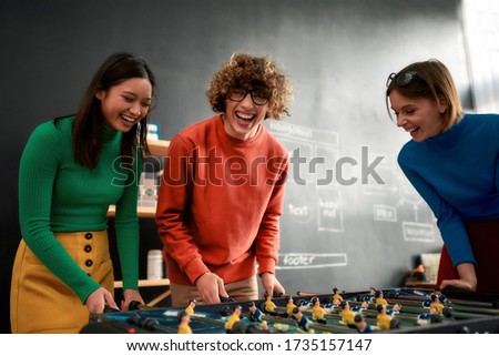 Group young and excited people in casual wear playing table soccer in the modern office and laughing. Office activities. Having fun together. Happy employees Royalty-Free Stock Photo #1735157147