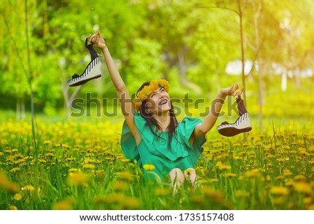 beautiful girl enjoys spring with a wreath of dandelions on her head