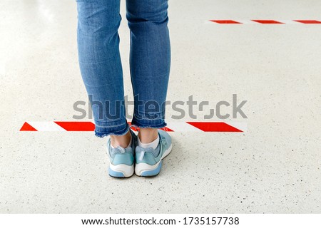 People stand in line keeping social distance, Woman standing behind a warning line during covid 19 coronavirus quarantine. Safe shopping, Social distancing concept. Legs in line close up