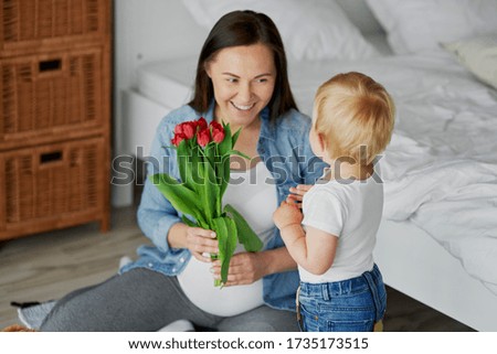 Toddler boy giving his mom a bunch of tulips