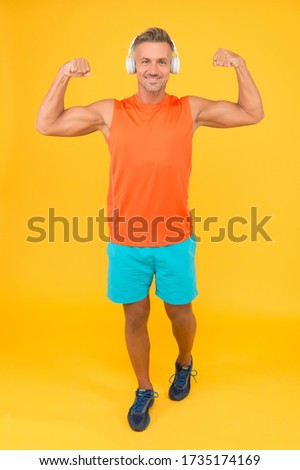 Music is power. Happy man fix arms yellow background. Fit guy show muscle power. Gym clothes and sportwear. Power and strength. Training for power. Fitness and sport. Healthy lifestyle.